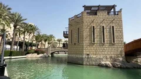 Tilt-Down Shot of Brick Building, Wooden Bridge, and Palm-Lined Canal Stock Footage 303371086