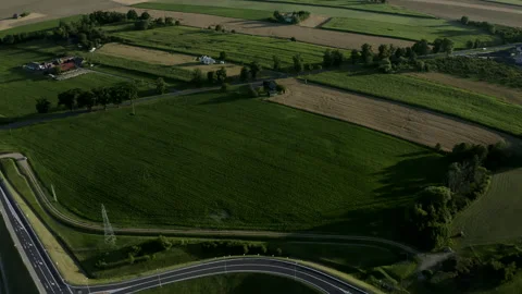 Tilt-Down Shot Flight Above Green Field And Multi-Level Junction Road Stock Footage 142003581