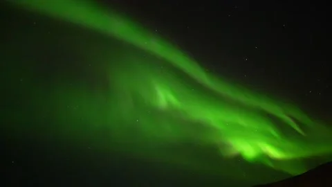 Tilt down shot illuminating Vik Town in Iceland with green Northern Lights Stock Footage 237742518