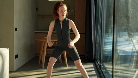 Tilt down shot of slim fit young woman in activewear making squats for glutes in Stock Footage 273175168