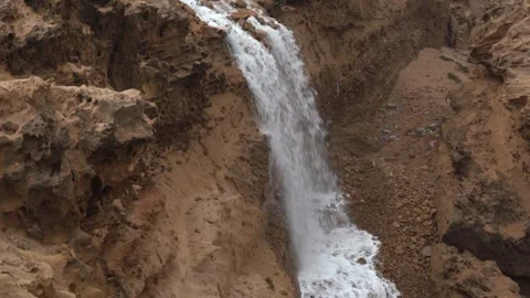 Tilt-Down Shot of Wastewater Runoff Cascading Over Eroded Cliff Near Housing Stock Footage 334182532