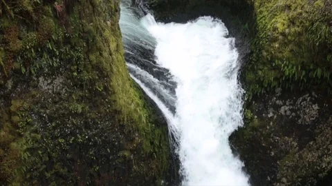 Tilt down shot of waterfall over rock formations at forest Stock Footage