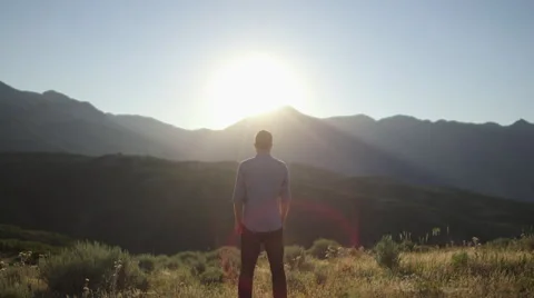 Tilt Down From Sky to Man Standing, Looking at Sunset Over Mountains 動画素材 68723672