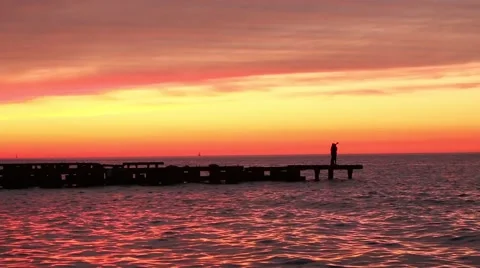 Tilt Down on Sunset Lake and Couple on Jumbled Pier Stock Footage 67553163