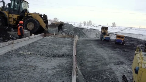 Tilt down tracking shot of bulldozer unloading freight train with copper ore at Stock Footage 75068614