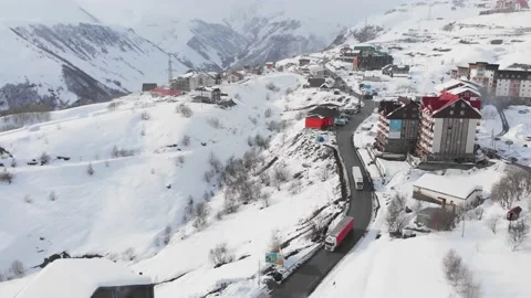 Tilt down view lorry trucks ride on snowy mountains Gudauri village. Stock Footage 151034304