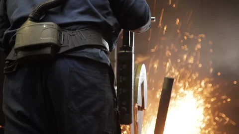 Tilt of a foundry worker using a circular saw Stock Footage 231496792