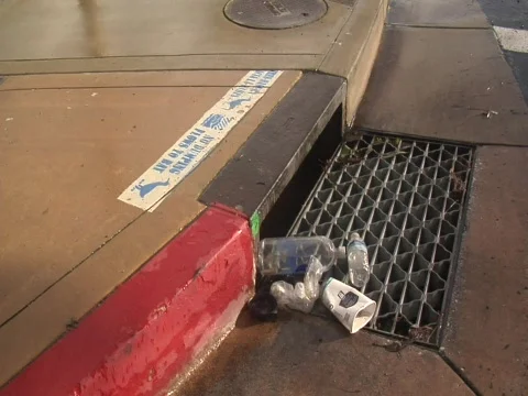 Tilt up from garbage on a storm drain Video stock 609996
