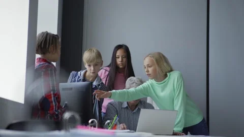 Tilt up of group of pupils standing at table with computer solving study task Stock Footage 142498478