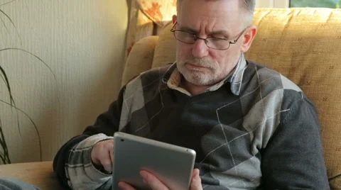 Tilt from hands to face of middle aged man at home using tablet Stock Footage 33213207