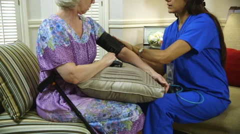 Tilt up to home healthcare nurse putting on blood pressure cuff Stock Footage