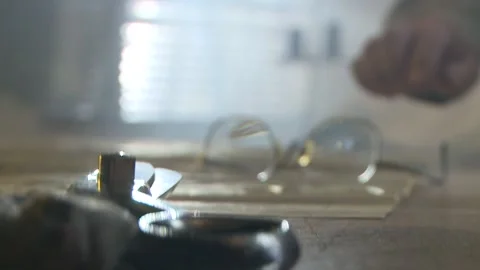 Tilt up of a man picking up his spectacles off the table Stock Footage 311924050