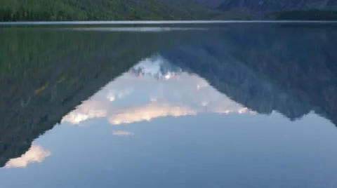 Tilt up to the mountain range reflecting in a mountain lake Stock-Footage 12568099