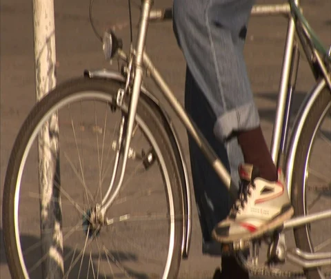 Tilt up to MS elderly man on bicycle, camera follows him into traffic Stock Footage 86742990