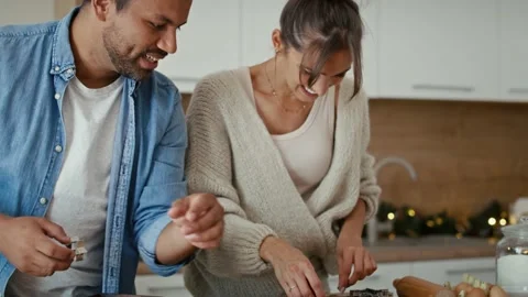 Tilt up of multi ethnicity couple making a gingerbreads in Christmas time Stock Footage 218807898