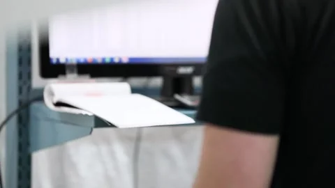A tilt up over the shoulder shot of man standing looking at computer Stock Footage 155533972