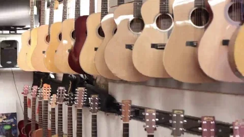 Tilt pan down row of acoustic guitars Stock Footage 69111347