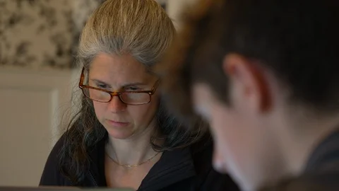 Tilt from parent to child’s computer and back doing school work Stock Footage 129640078