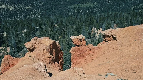 Tilt-Red rock cliff edge to distant pine valley Stock Footage 247339731