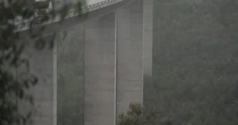 Tilt up from river to elevated bridge in rain Stock Footage 277389943