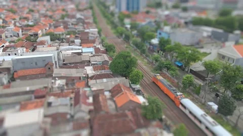 Tilt-shift Aerial View of a Passenger Train Passing Through Dense Urban Housing Vídeo Stock 334764441