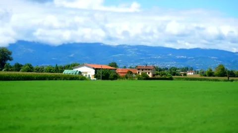 Tilt shift cloud timelapse over the mountains with farmland on the foreground Stock Footage 313799365