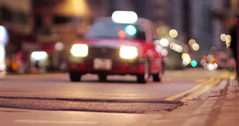 Tilt-shift defocused view of red taxi approaching Hong Kong street at night Stock Footage 324862097