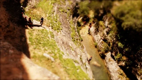 Tilt-shift: Miniature Canyoning group abseiling into a Canyon Stock Footage 98261700