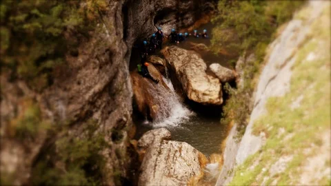 Tilt-shift: Miniature Canyoning group sliding down a  waterfall in single file Stock Footage 98296437