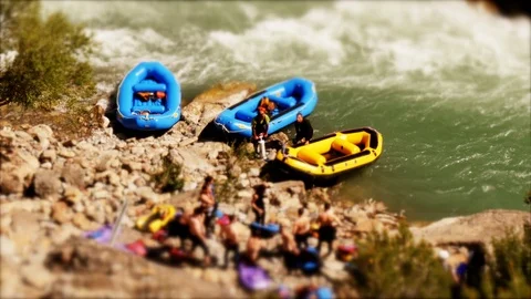 Tilt shift: Miniature man pumping up a raft at the river Stock Footage 98307443