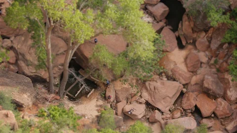 Tilt-shift overhead view of hikers hopping from boulder to boulder on hike Video stock 128840538