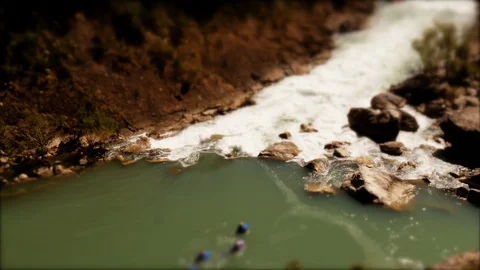 Tilt-shift: Tiny group with body boards entering white water rapids Stockbeeldmateriaal 98319392