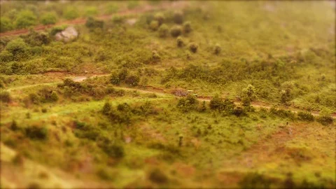 Tilt-Shift: Tiny Traktor passing trough mountains Stock Footage 98006243