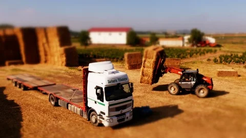 Tilt Shift Traktor loading hay bales on a truck. Fake miniature effect Stock Footage 97984851