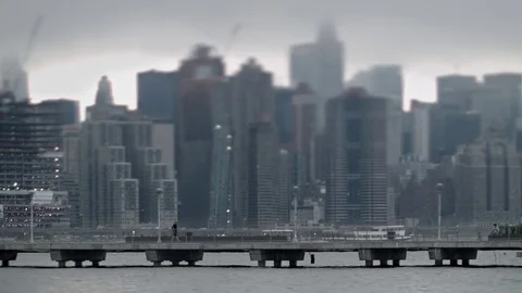 Tilt-shift view of man on footbridge. Manhattan waterfront buildings.  New York. Stock Footage 75271186