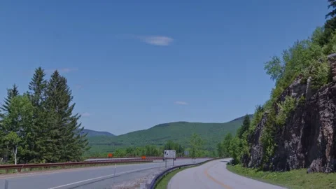 Tilt shot from blue sky to empty highway road in Franconia Notch, New Hampshire Stock Footage 338431677
