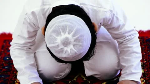 Tilt up shot of a boy praying during Eid festival Stock Footage 30046969