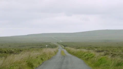 Tilt shot from cloudy skies to a single-track peat road Stock Footage 332155833