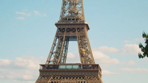 Tilt shot of the Eiffel tower, set against a bright sky with scattered clouds Stock Footage 313412409