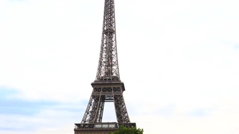 Tilt up shot of Eiffel Tower surrounded by trees. Iconic symbol of Paris, France Stock Footage 237923893