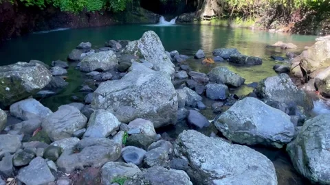 Tilt up shot of a hidden emerald lagoon and waterfall in the jungle of Bali Stock Footage 336904276