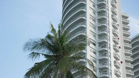 Tilt up shot of high multi-storey white hotel building on the beach with coconut Stock Footage 285710173