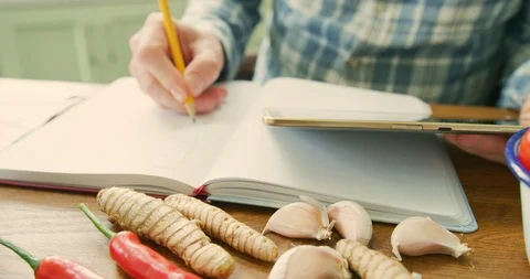 Tilt Up Shot Of Man Using Digital Tablet While Writing Recipe By Spices 4K Stock Footage 92379472