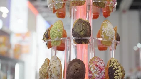 Tilt shot of multiple cakes with icing displayed on a vertical rotating holder. Stock Footage 304316950