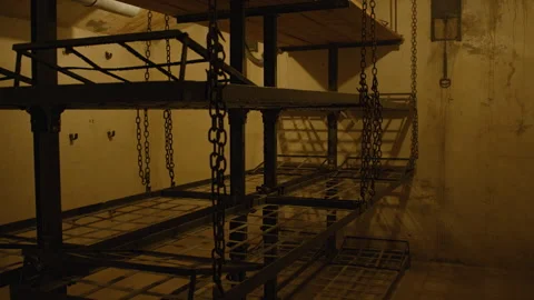 Tilt shot of old bunk beds with wooden planks on top, suspended by chains.  Stock Footage 301031198