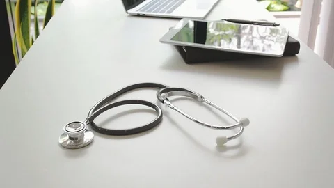 Tilt up shot of stethoscope with digital tablet and laptop at doctor's desk. Stock Footage 105471036