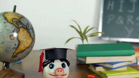 Tilt shot - Teacher's table with a globe, books, college degree, and a money ... Video stock 156231810