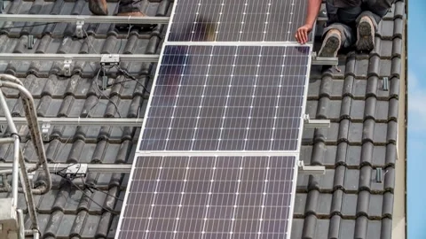 Tilt up shot of two workers installing solar panel cells on roof during Stock Footage 154741694