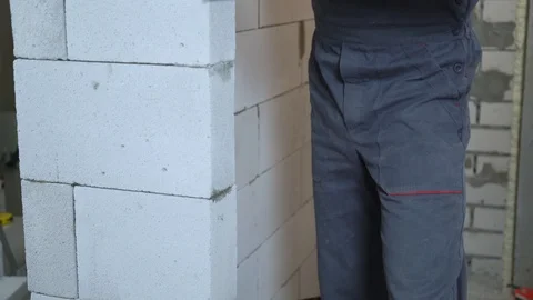 Tilt shot of young builder in work wear grinding block wall with abrasive tool Stock Footage 106768512