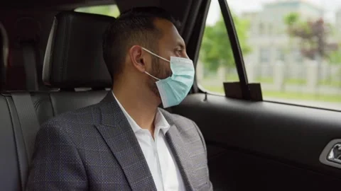 Tilt up side view of young Middle Eastern businessman in suit and face mask w Stock Footage 134760439